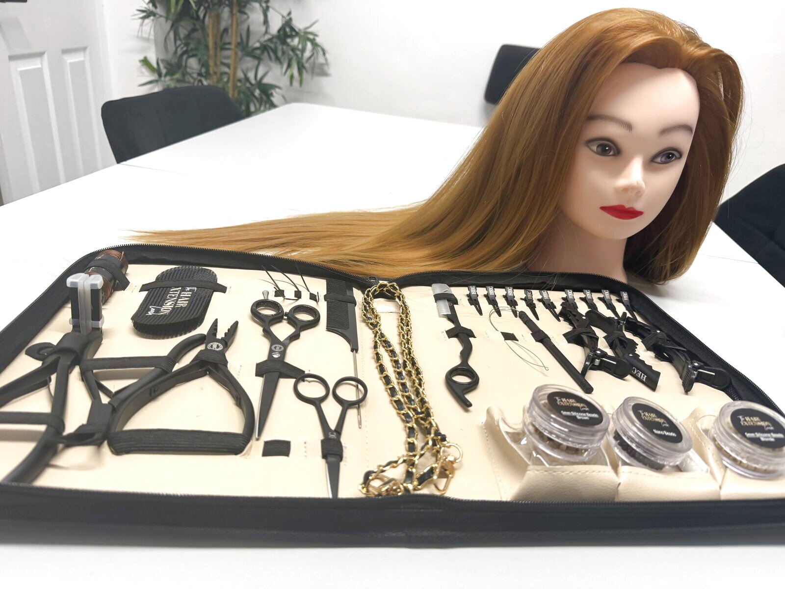 Matte black hair extension tool kit open with a practice head